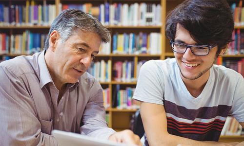 A student and advisor having a conversation in a library. 